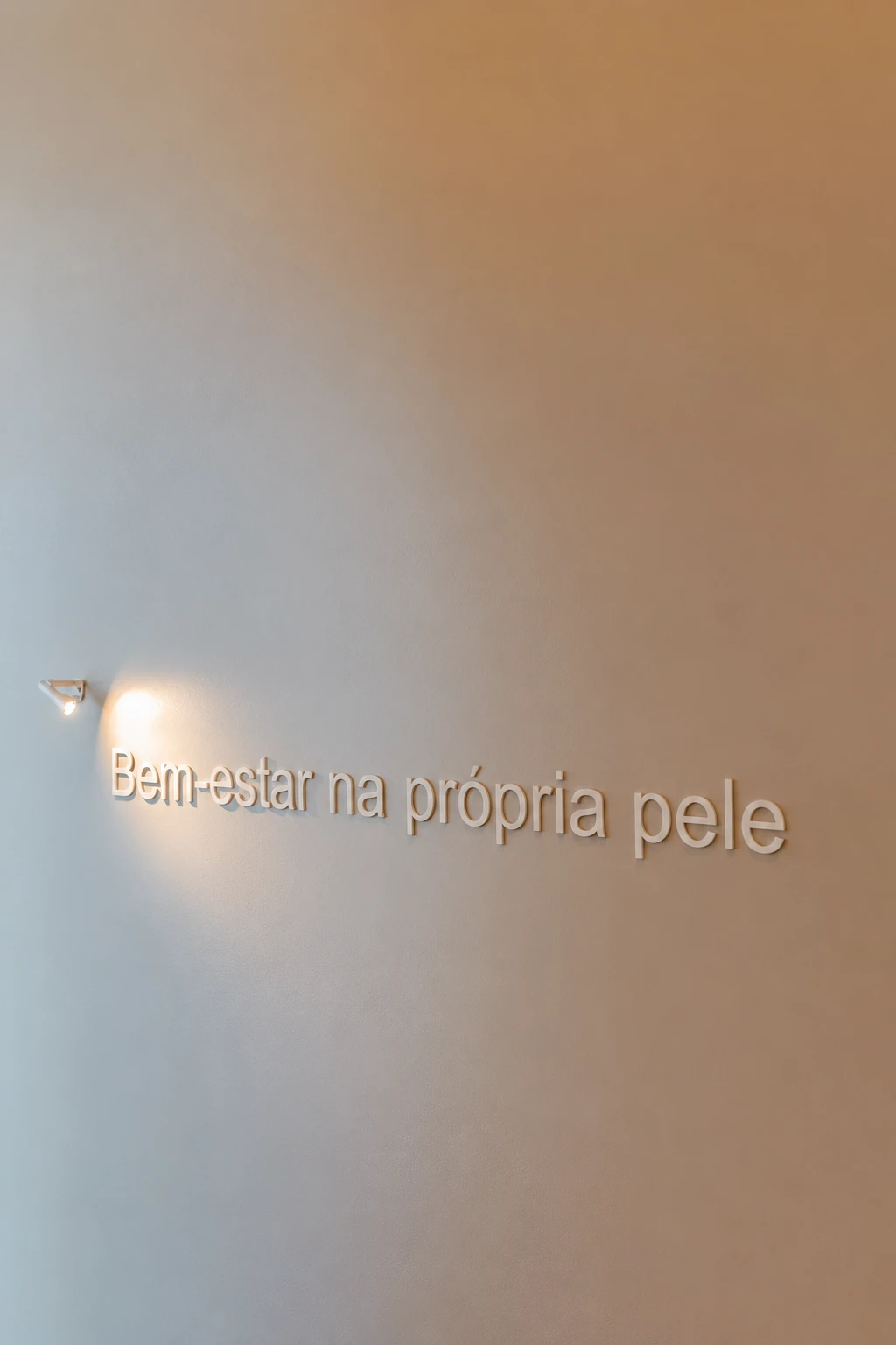 Frase 'Bem-estar na própria pele' gravada na parede da Clínica Balma